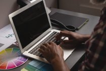 Diseñador gráfico senior usando portátil en el escritorio en la oficina - foto de stock
