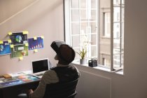 Diseñador gráfico senior usando auriculares de realidad virtual en la oficina - foto de stock