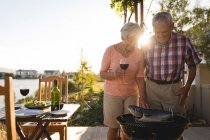 Senior couple cooking fish on barbeque in the backyard — Stock Photo
