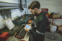 Механік з використанням цифрового планшета на робочій лавці в ремонтному гаражі — стокове фото