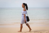 Улыбающаяся красивая женщина, гуляющая по песку на пляже — стоковое фото