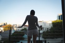 Vista posteriore della donna in piedi sul balcone a casa — Foto stock