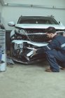 Mecânico examinando carro danificado na garagem de reparação — Fotografia de Stock