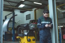 Mechaniker mit Handy in Reparaturwerkstatt — Stockfoto