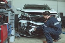 Механик осматривает поврежденный автомобиль в ремонтном гараже — стоковое фото