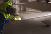 Ingeniero examinando la luz de la aeronave en el hangar aeroespacial — Stock Photo