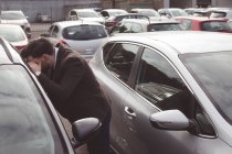 Salesman прокрадається крізь вікно автомобіля за межами вітрини — стокове фото