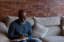 Старший чоловік пише в щоденнику вдома — стокове фото