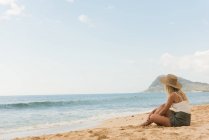 Frau mit Hut entspannt am Strand an einem sonnigen Tag — Stockfoto