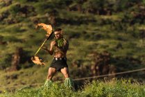Чоловіча танцівниця вогню, що виступає з вогнем levi stick біля пляжу — стокове фото