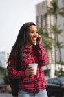 Улыбающаяся женщина разговаривает по мобильному телефону на городской улице — стоковое фото