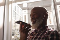 Diseñador gráfico senior hablando en el teléfono móvil en la oficina - foto de stock