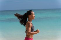 Frau joggt an einem sonnigen Tag am Strand — Stockfoto