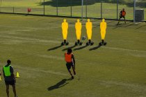 Jugadores practicando fútbol en el campo en un día soleado - foto de stock
