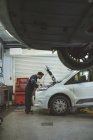 Mecánico masculino servicio de coches en el garaje de reparación - foto de stock