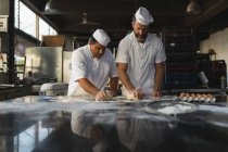 Bäcker bereitet Teig mit seinem Mitarbeiter in Backstube zu — Stockfoto