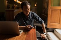 Концентрований бізнесмен за допомогою мобільного телефону в кафе — стокове фото