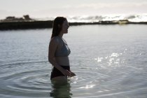 Счастливая женщина стоит в бассейне в солнечный день — стоковое фото