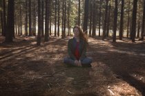 Woman doing meditation in forest on sunny day — Stock Photo