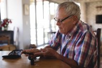 Senior man checking his blood sugar with glucometer at home — Stock Photo