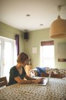 Femme utilisant un ordinateur portable dans le salon à la maison — Photo de stock