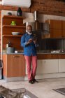 Старший чоловік, що стоїть на кухні під час користування цифровий планшетний вдома — стокове фото
