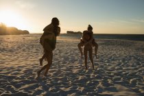 Jugadoras de voleibol divirtiéndose en la playa al atardecer - foto de stock
