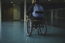 Handicapped man on wheelchair moving in passage at gym — Stock Photo