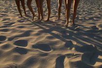 Sección baja de jugadoras de voleibol corriendo en la playa - foto de stock