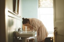 Mulher lavando o rosto no banheiro em casa — Fotografia de Stock