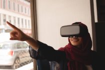 Businesswoman in hijab using virtual reality headset at office cafeteria — Stock Photo