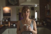 Ritratto di bella donna che tiene una tazza di caffè a casa — Foto stock