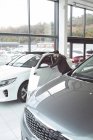 Vendeur examinant la voiture au showroom — Photo de stock