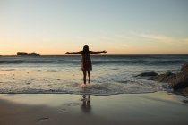 Женщина-волейболистка стоит с распростертыми на пляже руками — стоковое фото