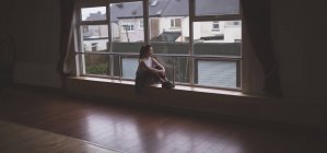 Danseuse réfléchie regardant par la fenêtre dans le studio de danse — Photo de stock