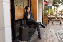 Улыбающийся бизнесмен разговаривает по телефону в тротуарном кафе — стоковое фото