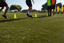 Giocatori di calcio dribbling palla attraverso coni in campo sportivo — Foto stock