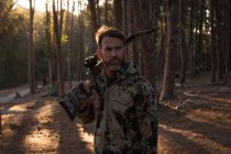Задумчивый охотник с луком и стрелами стоит в лесу — стоковое фото