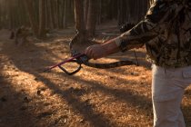 Sección media del cazador lista para disparar con arco y flecha en el bosque - foto de stock