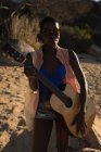 Жінка тримає гітару на пляжі в сонячний день — стокове фото
