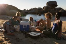 Группа друзей, взаимодействующих друг с другом на пляже в солнечный день — стоковое фото