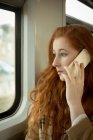 Красивая женщина разговаривает по мобильному телефону во время поездки на поезде — стоковое фото