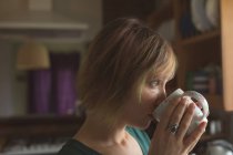 Schöne Frau mit Tasse Kaffee in der Küche zu Hause — Stockfoto