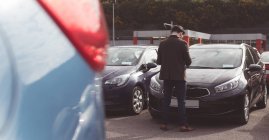 Rear view of salesman standing next to car outside the showroom — Stock Photo