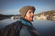 Junger männlicher Wanderer steht mit Rucksack am See — Stockfoto