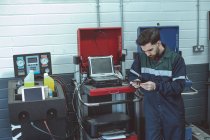 Mecânico atencioso usando telefone celular na garagem de reparação — Fotografia de Stock