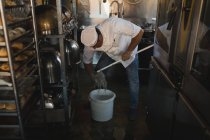 Cocinero masculino limpiando piso con fregona en panadería - foto de stock