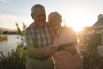 Щаслива старша пара використовує мобільний телефон на задньому дворі — стокове фото
