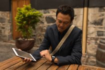 Empresário sorridente olhando para smartwatch no café pavimento — Fotografia de Stock