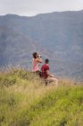 Hiker couple sitting in countryside, girl drinks from a thermos bottle — Stock Photo